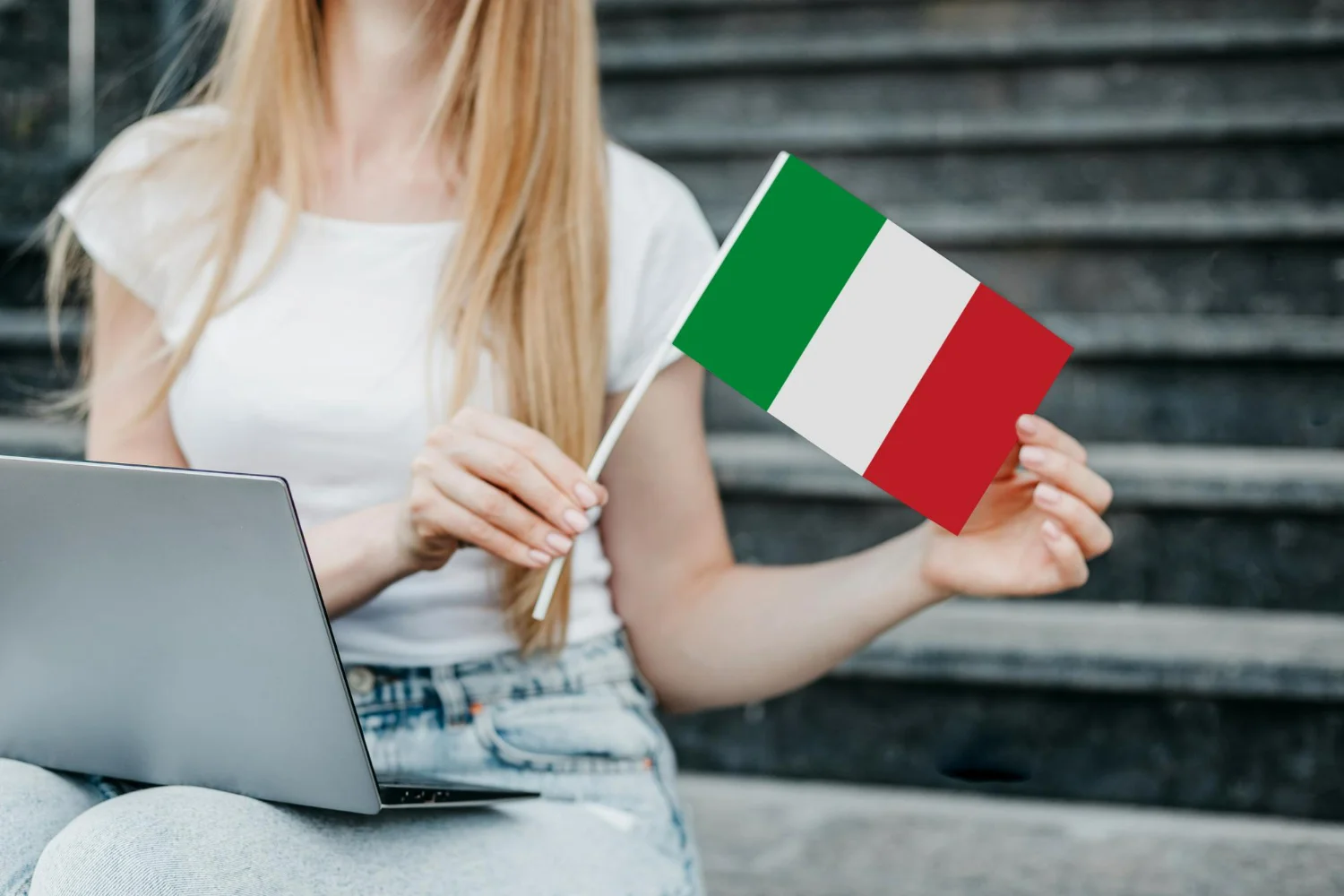 Mulher com notebook no colo segurando bandeira da Itália após atualizar seu AIRE Itália