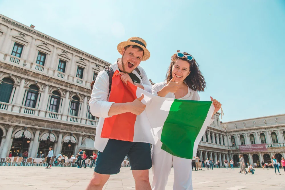 Casal feliz segurando bandeira da Itália após verificar quanto tempo demora a cidadania italiana