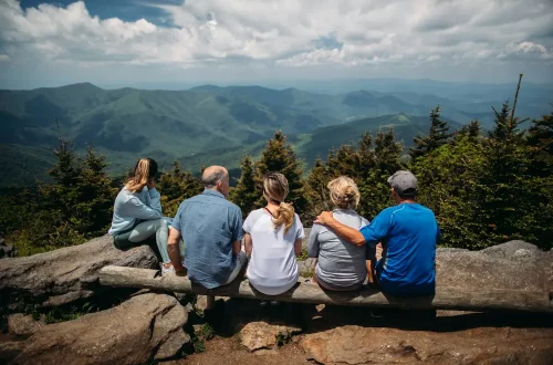 Foto de uma família de diversas gerações olhando para uma paisagem montanhosa