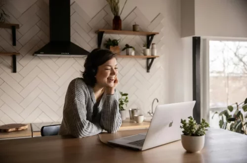 Mulher feliz em frente ao notebook descobrindo como saber se sua cidadania italiana foi aprovada